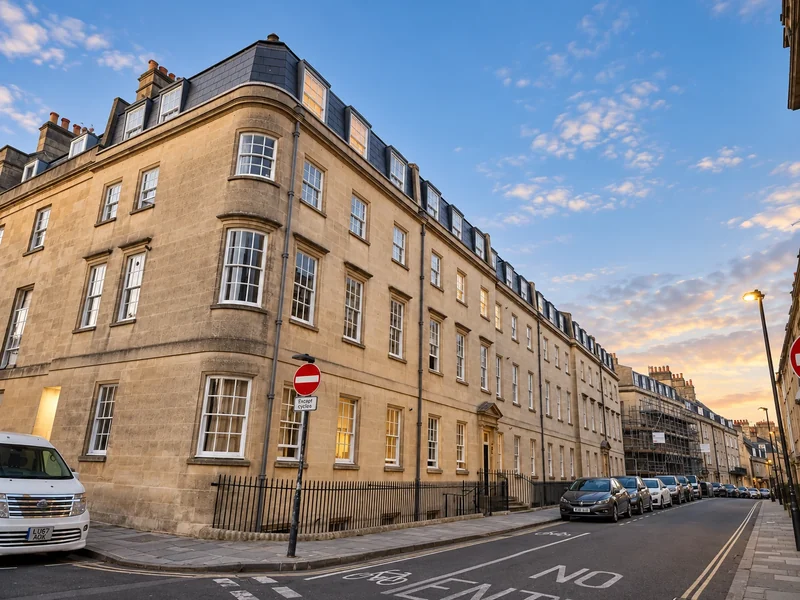 Bath stone residential block at dusk with the completed roof and dormers above