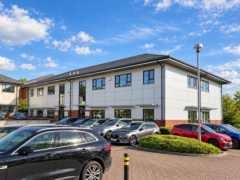 Two-storey office building and car park under a blue sky