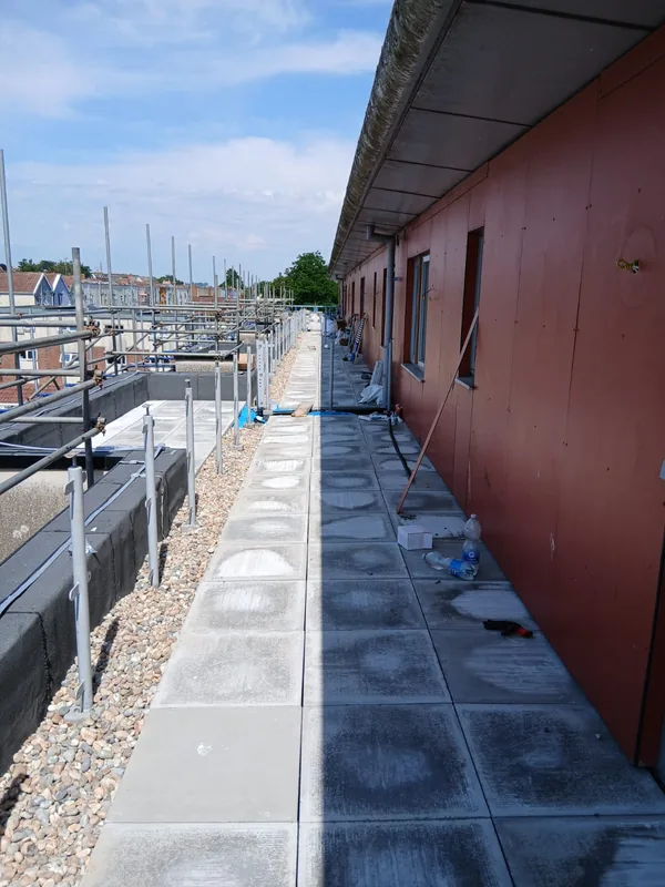 Long balcony walkway with new paving and gravel margins