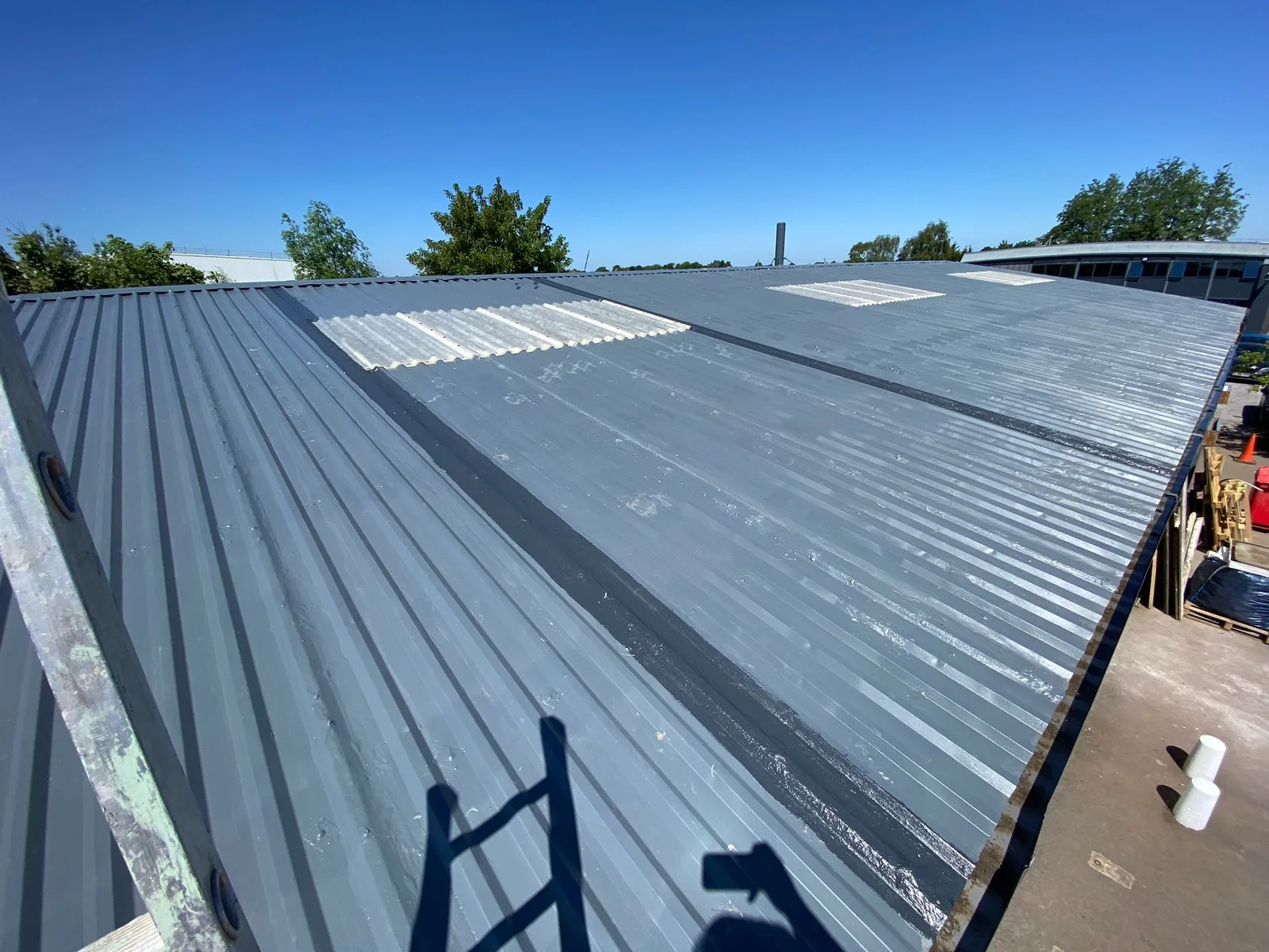 Metal roof of an industrial unit after overcoating with a grey liquid waterproofing system