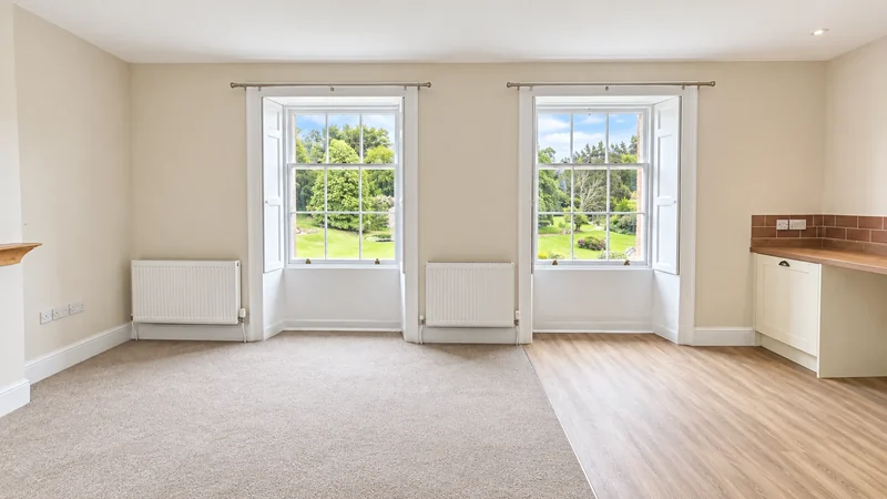 Refurbished room with new kitchenette units beneath tall sash windows