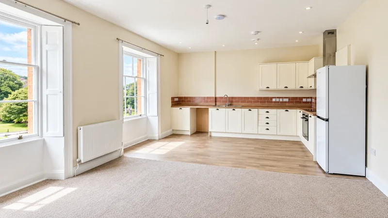 Open-plan living room in a converted flat with kitchen run and sash windows