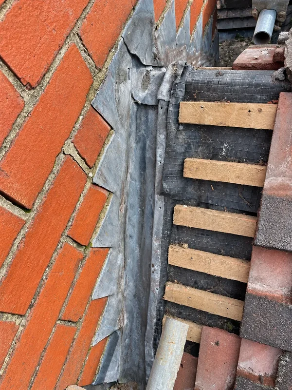 Decayed brickwork and failed lead on a school chimney before repair